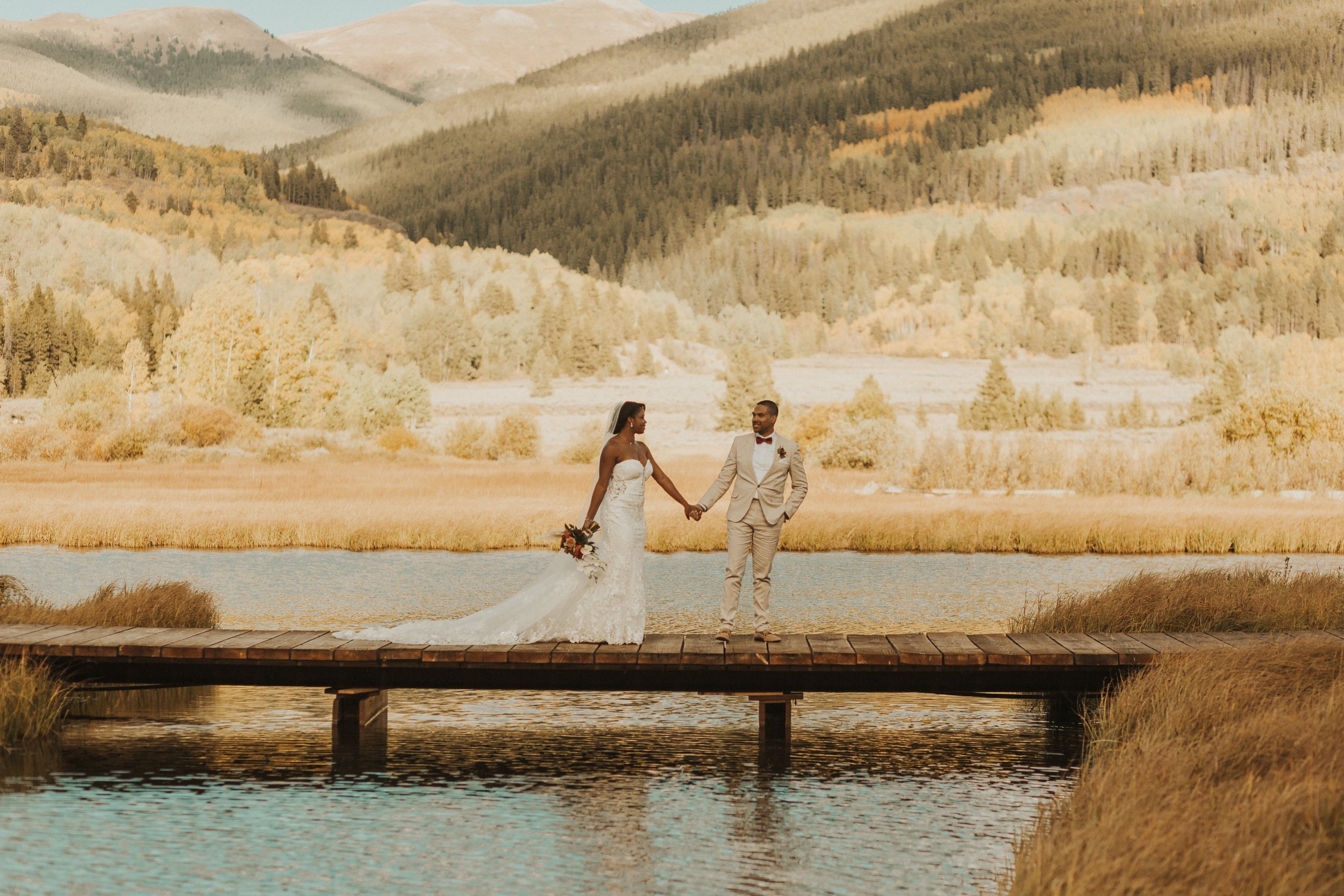 bride and groom posed on dock over the water in CO
